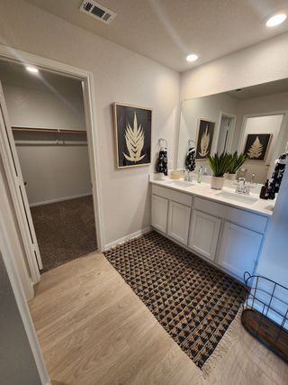A sleek and stylish bathroom with a double vanity, modern fixtures, and a spacious walk-in closet.