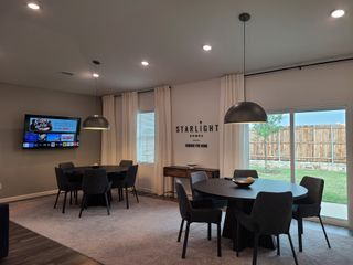 A modern dining area with sleek black tables, cozy chairs, oversized pendant lights, and a large window offering natural light.