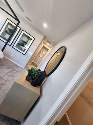 Model Home A modern bedroom with chic decor, including framed art, a round mirror, and sleek furnishings.