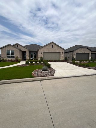 Street view A beautiful brick home with manicured lawn in Del Webb at Trinity Falls by Del Webb (McKinney, TX).