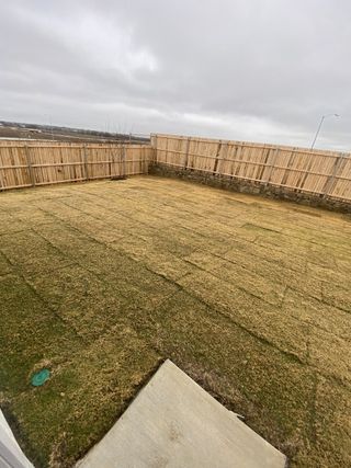 A private backyard with fresh sod and wooden fencing in Deer Creek: Watermill Collection by Lennar (Crowley, TX).