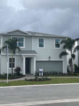 A modern gray home with palm trees and landscaped yard in Forest by Mattamy Homes (Lake Worth, FL).