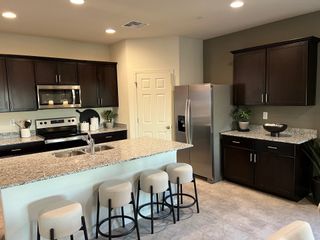 Modern kitchen with sleek dark cabinets, granite countertops, stainless steel appliances, and a cozy island with stools.