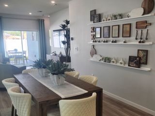 Model Home A chic dining area with quilted chairs, wood accents, and wall decor, seamlessly flowing into the open-concept living space.