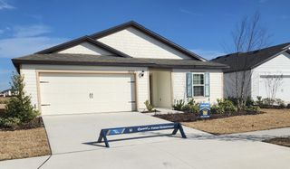 A charming cream home with blue shutters and manicured lawn in Rolling Hills by LGI Homes (Green Cove Springs, FL).