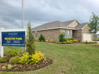 Street view A charming brick home with lush landscaping in Meadow Park by Starlight Homes (Melissa, TX).