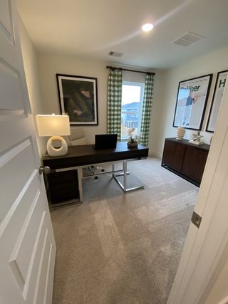 Model Home A sophisticated home office with a large window, green plaid curtains, and cozy carpeting for a productive space.