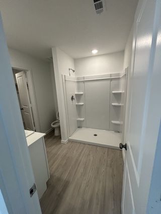 A modern bathroom featuring a spacious shower, sleek flooring, and minimalist design.
