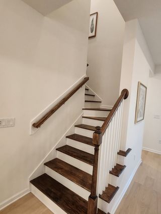 Model Home A modern staircase featuring dark wood steps and elegant white railings, complemented by light walls and framed art.