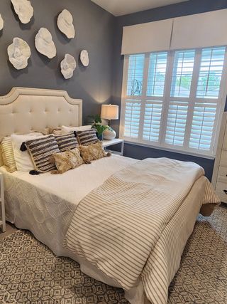 A cozy bedroom retreat with a tufted headboard, deep blue accent wall, and textured décor, creating a stylish and serene space.