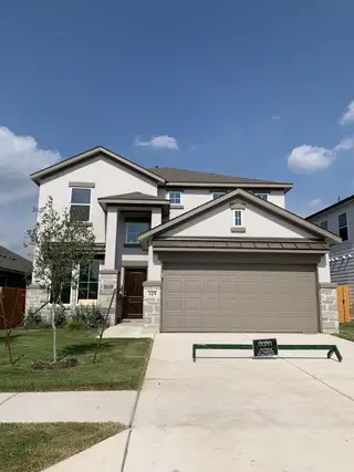 A modern two-story home with a manicured lawn in Morningstar by Saratoga Homes (Georgetown, TX).