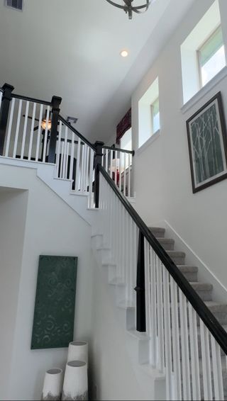 Model Home Elegant staircase with white railings and modern decor, featuring artwork and sleek lighting.