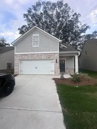 A charming gray brick home with a spacious driveway in Towne Center by DRB Homes (Hampton, GA).