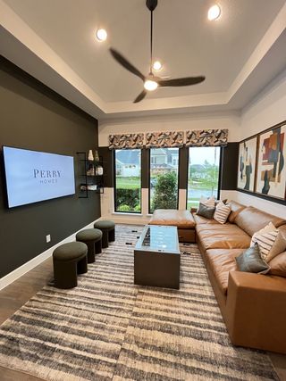 A cozy living room with a large leather sectional sofa, stylish decor, and ample natural light from wide windows.