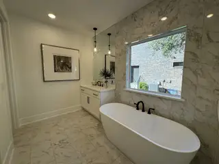 A modern bathroom with marble tiles, a sleek freestanding tub, dual sinks, and contemporary lighting.