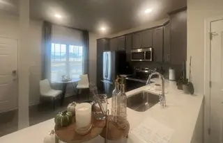 A modern kitchen with sleek gray cabinets, stainless steel appliances, and a cozy dining nook by the window.