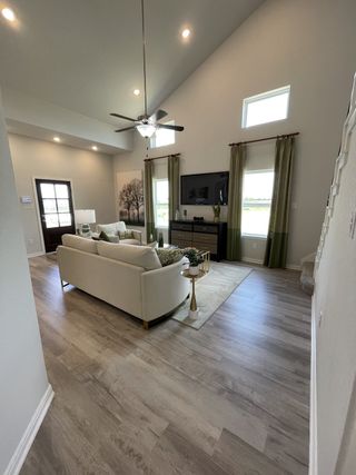 A spacious living room with vaulted ceilings, elegant beige furnishings, and natural light from high windows.