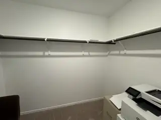 Model Home A spacious walk-in closet with ample shelving and a modern printer setup, offering convenience and organization.