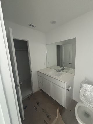 Model Home A modern bathroom featuring a sleek white vanity, large mirror, and minimalistic design.