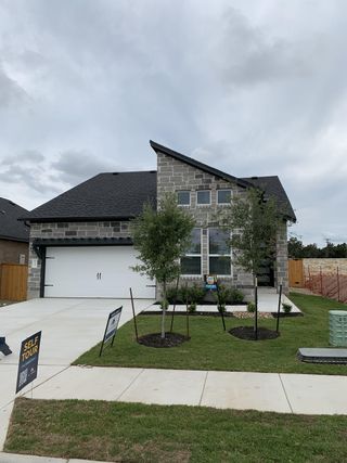 Street view A contemporary stone-clad home with lush landscaping in Cedar Brook by M/I Homes (Leander, TX).
