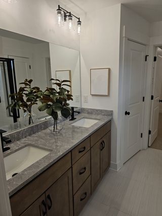 Model Home A stylish bathroom with a dual-sink vanity, granite countertops, and modern lighting for a sleek and functional design.