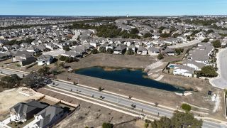 Street view Aerial view of suburban homes with a pond in the River Bluff community by KB Home (Leander, TX).