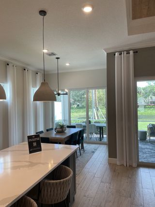 A modern dining area with large windows, a sleek island, and elegant pendant lighting, creating an inviting open space.