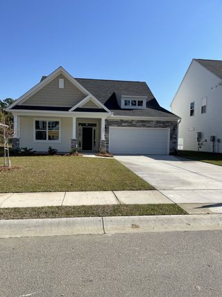 Charming home with stone accents and manicured lawn in Oakley Pointe by Eastwood Homes (Moncks Corner, SC).