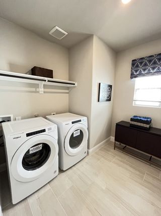 A modern laundry room with sleek white appliances, ample storage, and stylish decor.