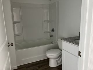 Model Home A modern bathroom featuring a sleek tub, granite vanity, and elegant flooring.