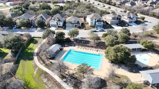 Aerial view of a charming neighborhood pool and park in Weston Oaks 55' by Perry Homes, nestled in San Antonio, TX.