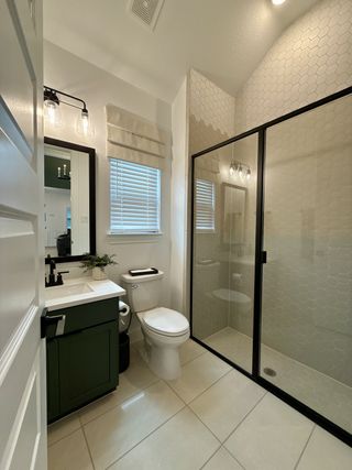 A modern bathroom featuring a sleek black-framed shower, white vanity, and stylish lighting.