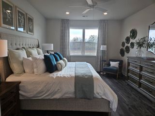 Model Home A spacious bedroom with a tufted headboard, green accents, and large windows in Oak Ridge Meadows by D.R. Horton (Locust Grove, GA).