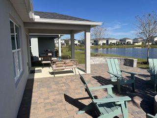 A serene patio overlooking a pond with cozy seating in Gardens at Waterstone III by KB Home (Palm Bay, FL).