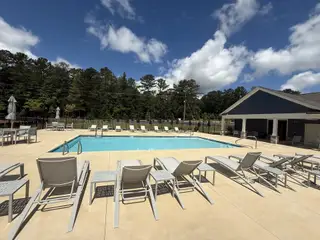 A pristine community pool with lounge chairs and a clubhouse in Candleberry Place by Lennar (Sharpsburg, GA).