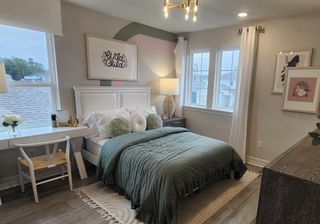 A cozy bedroom with a stylish green bedspread, accent decor, and a functional study area near the window.