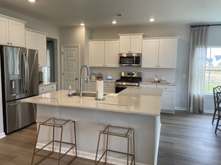 A modern kitchen with white cabinetry, stainless steel appliances, and a spacious island.