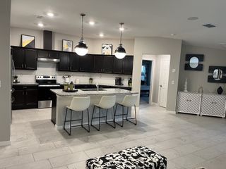 A modern kitchen with dark cabinets, granite countertops, and sleek lighting, featuring a cozy dining area and stylish decor.