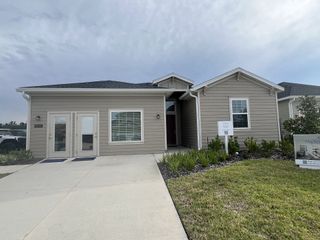 A charming single-story home with beige siding and neat landscaping in Saddle Oaks: Saddle Oaks 40s by Lennar (Jacksonville, FL).