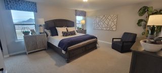 Model Home A spacious master bedroom with serene décor, including cozy bedding and a relaxing color palette.