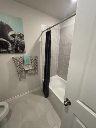 A cozy bathroom featuring a tiled tub, soft gray accents, and vibrant artwork for a modern touch.