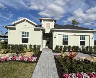 A charming light-colored home with lush landscaping in The Timbers at Everlands by Lennar (Palm Bay, FL).