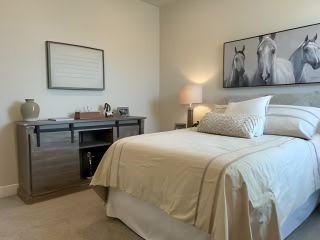 A cozy bedroom with soft lighting, neutral tones, equestrian artwork, and modern furnishings for a serene atmosphere.