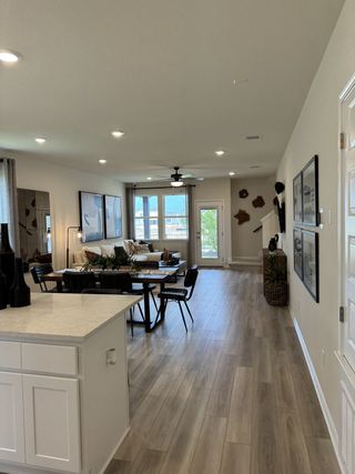 Model Home An open-concept living and dining area with wood flooring, modern decor, and ample natural light streaming through large windows.