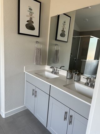 Model Home Modern bathroom featuring a dual-sink vanity, sleek cabinetry, and wall art for a stylish touch.