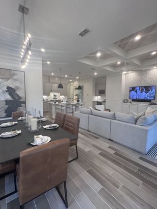 Model Home A modern living and dining area with sleek furnishings, neutral tones, and stylish lighting fixtures.