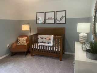 A cozy nursery featuring a wooden crib, comfy armchair, and soft lighting with playful wall art accents.