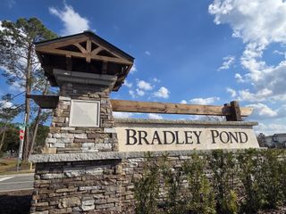 A welcoming stone entrance sign for Bradley Pond by Pulte Homes in Jacksonville, FL, set against a bright blue sky.