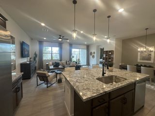 Model Home A modern open-concept living area with granite island, pendant lights, and cozy seating.