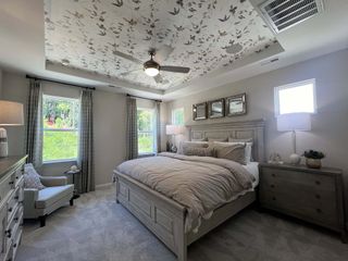 Elegant bedroom with floral ceiling, cozy bedding, mirrored accents, and abundant natural light.